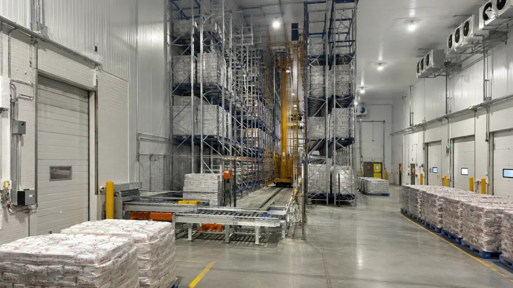Cold Storage ASRS: Automation in Sub-Zero Warehouses Cold storage ASRS warehouse with high-bay freezer racks, pallet crane aisles, insulated doors, conveyors, and staged frozen goods ready for outbound shipping